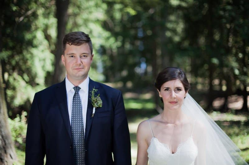 Woodsy wedding photo of bride and groom with evergreen forest behind them