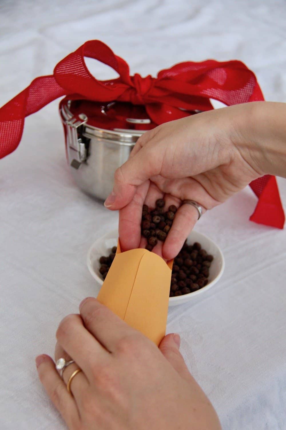 Two hands pouring seeds into a small envelope to make a diy valentine gift