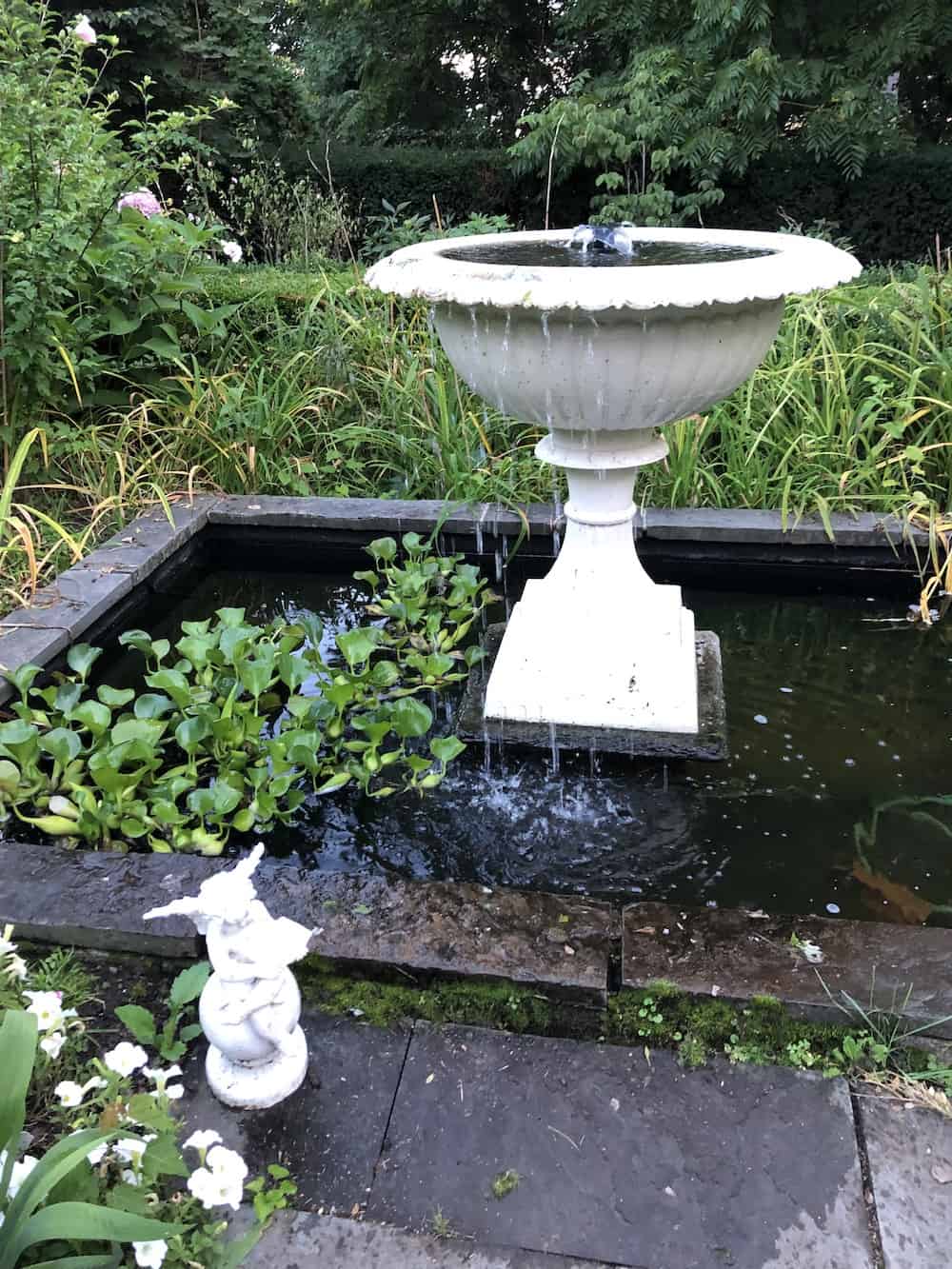 White painted concrete birdbath with fountain and pond
